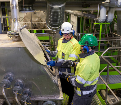 image of two persons in front of a piece of process equipment